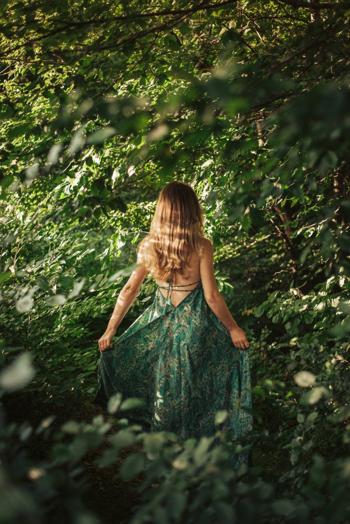 O femeie în rochie verde, mergând printr-o pădure deasă