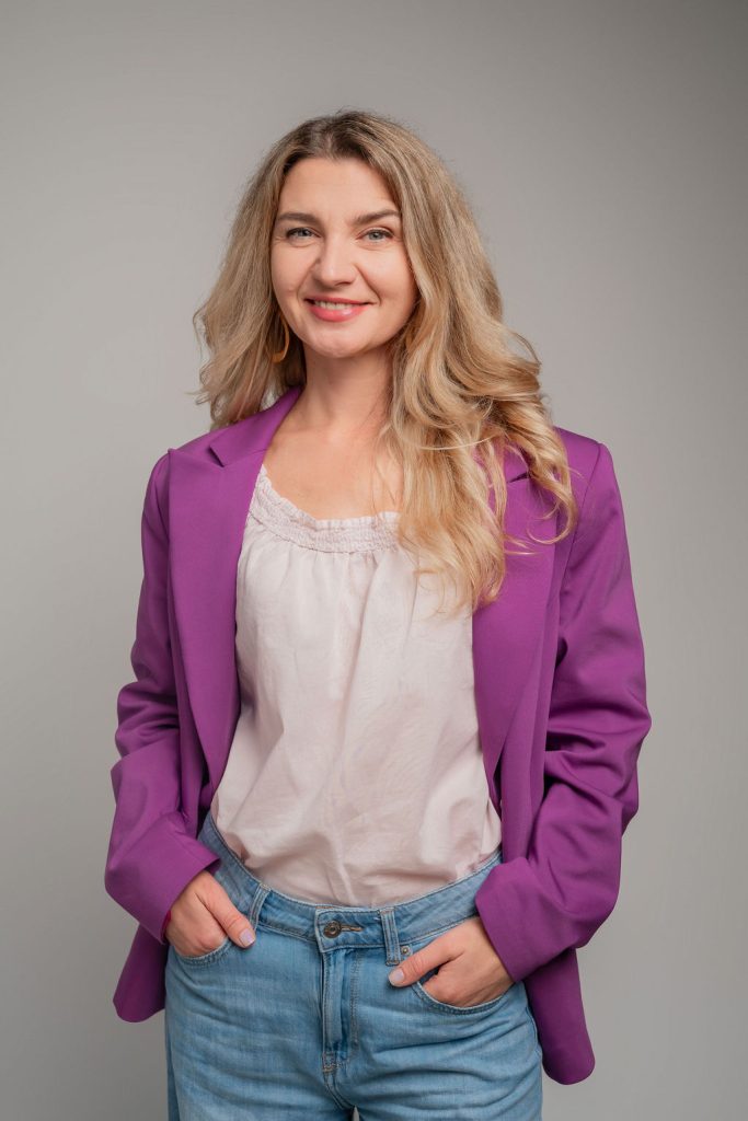 Adela Haru în sacou mov și blugi, zâmbind: ședințe de coaching individual